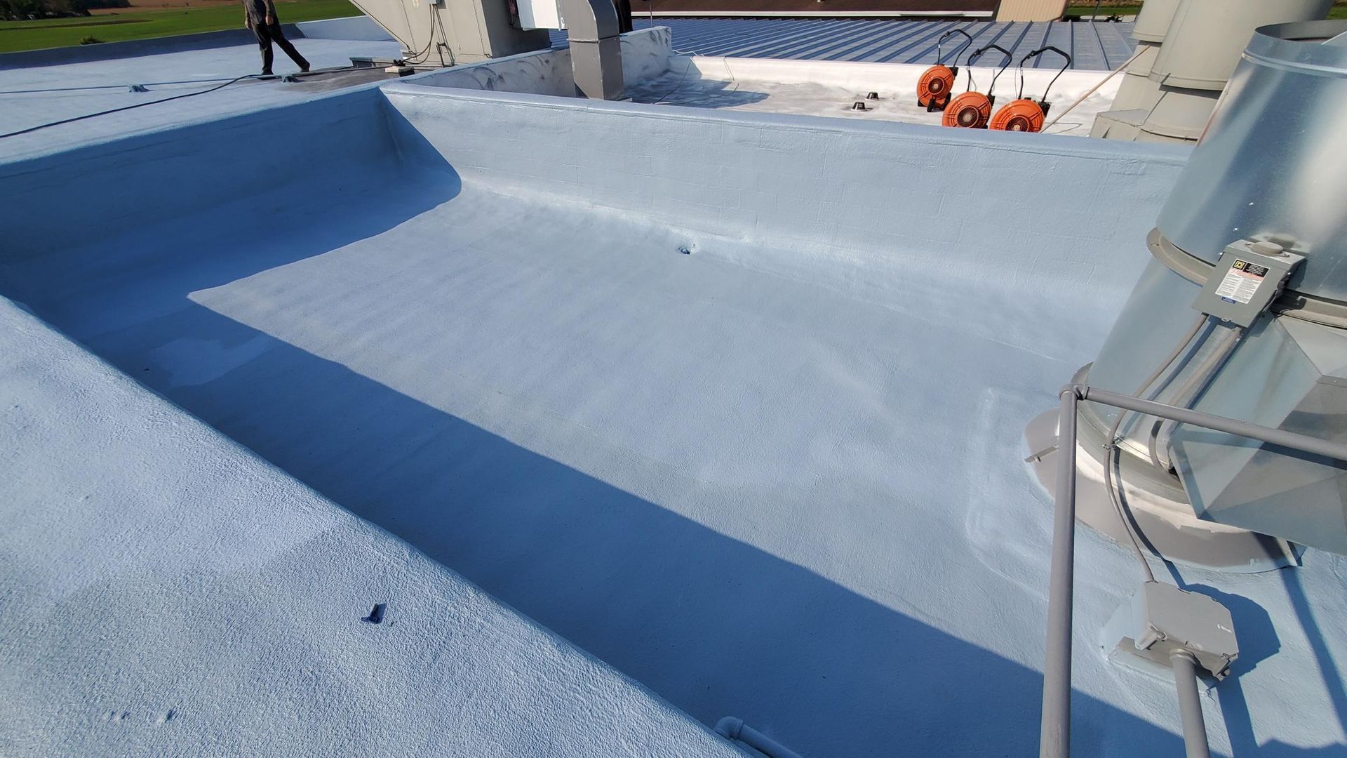 A person is standing on top of a white roof.