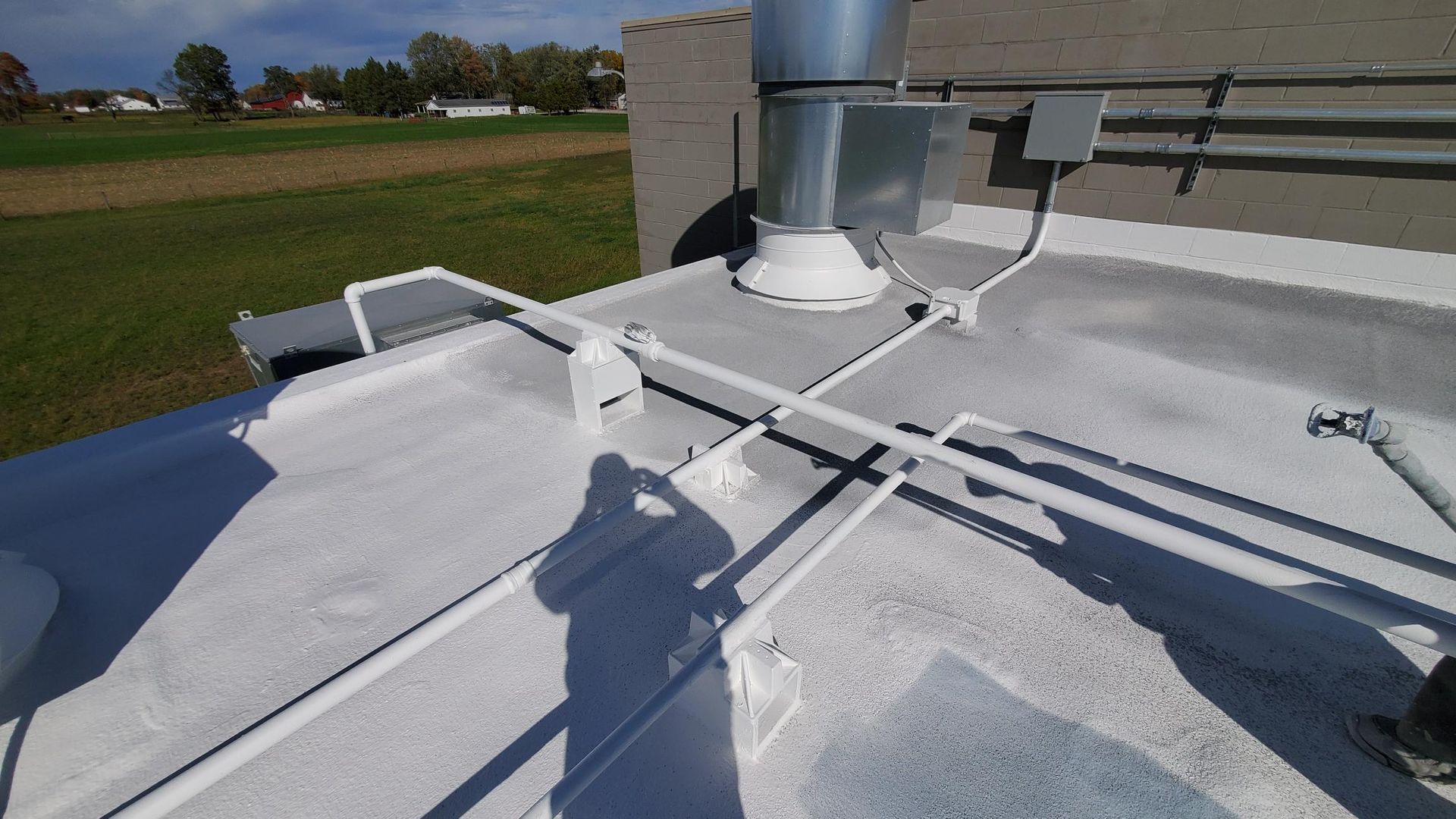 A roof with a lot of pipes on it and a shadow of a person on it.