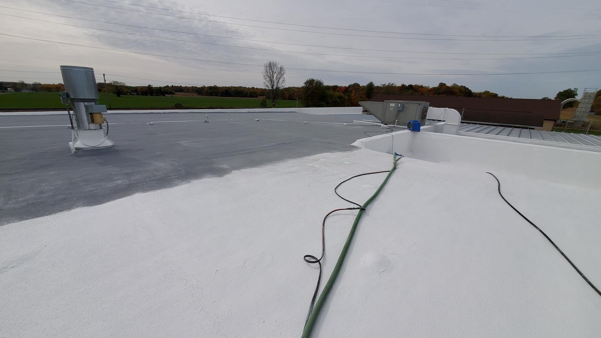 A roof with a hose attached to it is being painted white.