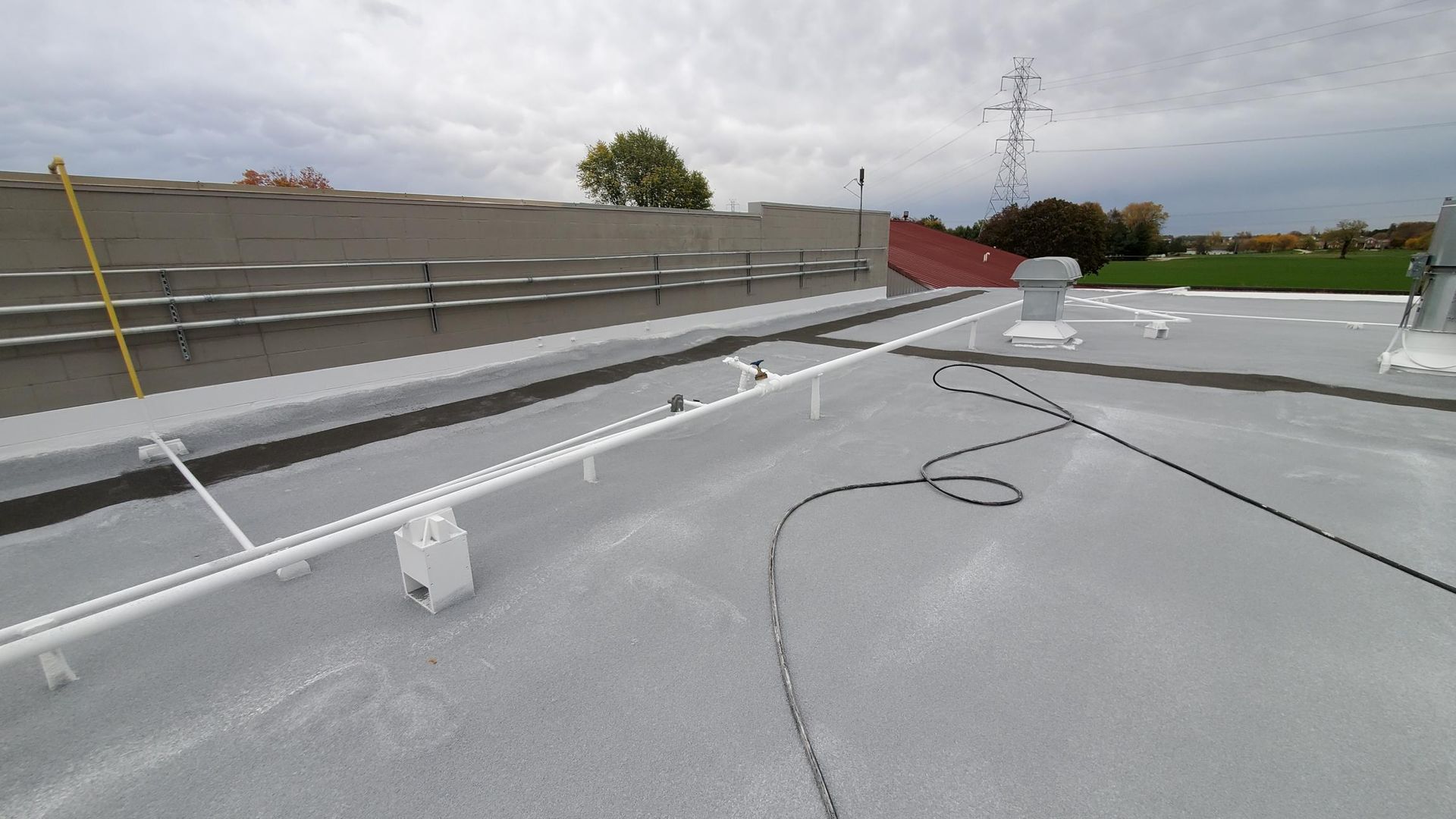 A roof with a hose attached to it and a fence in the background.