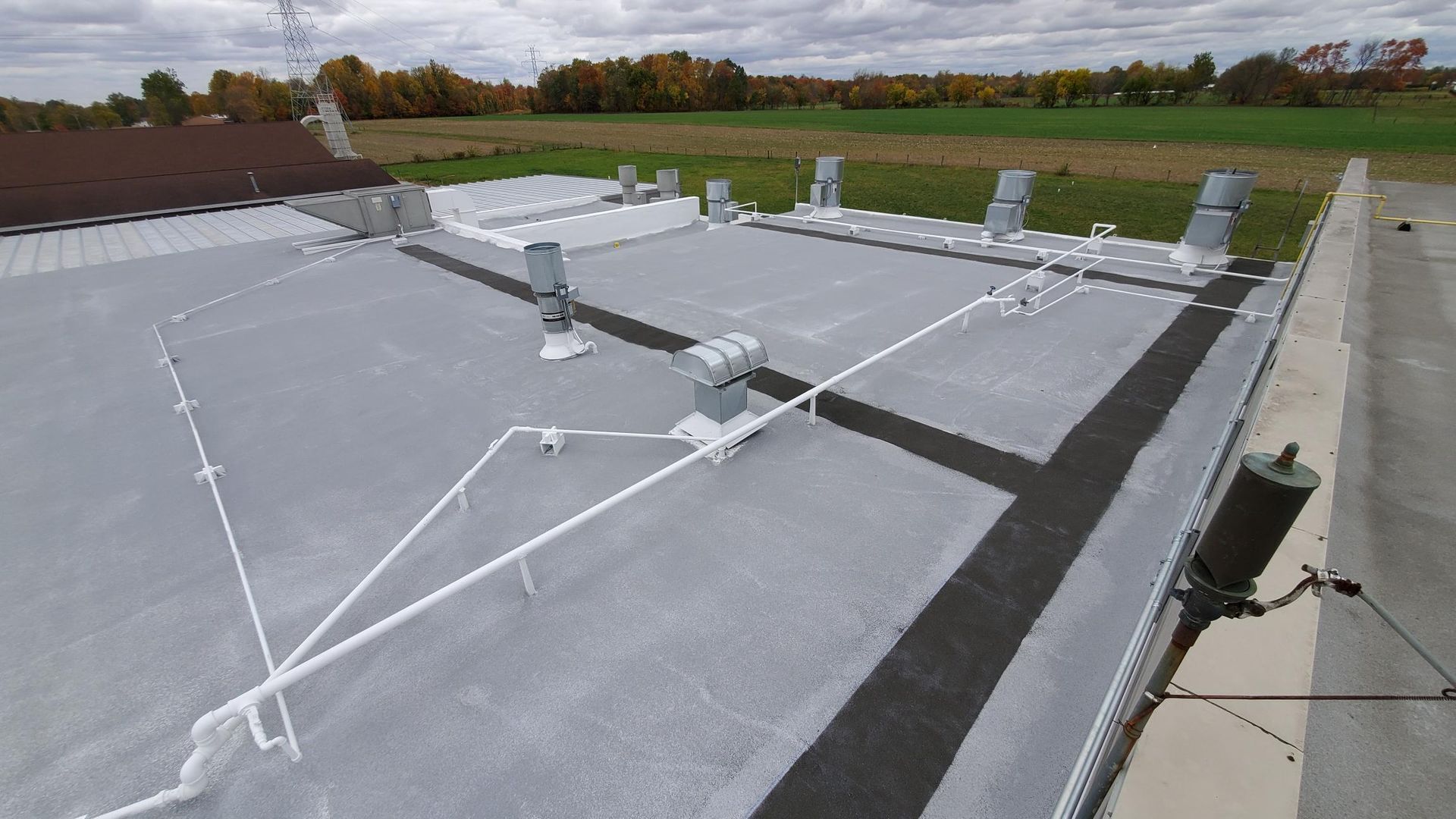 A roof with a lot of wires on it and a field in the background.