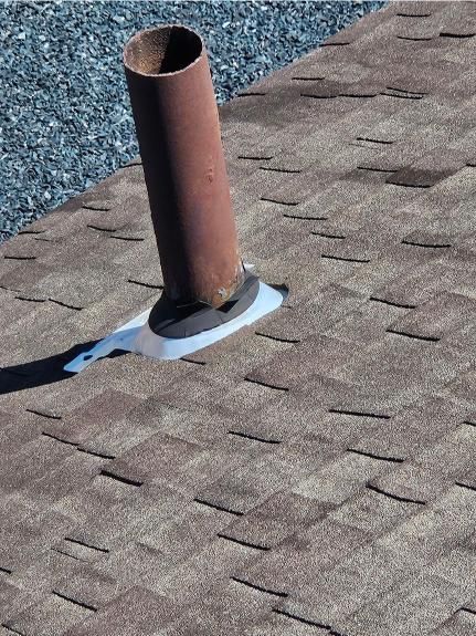 A brown pipe is sitting on top of a roof.