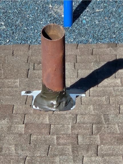 A pipe is sitting on a brick floor next to a blue pole