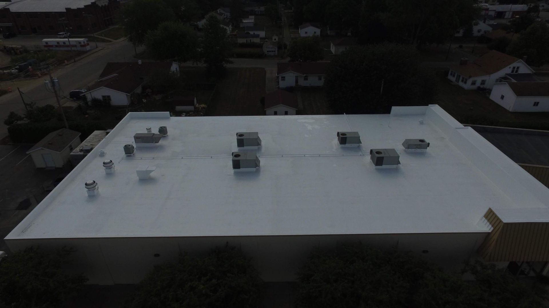 An aerial view of a white roof with a lot of vents on it.