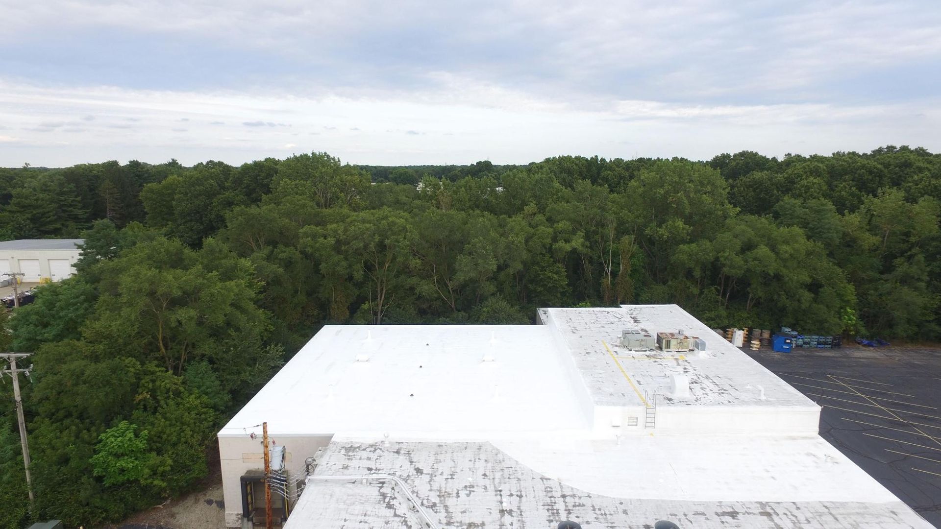 An aerial view of a white roof with trees in the background.