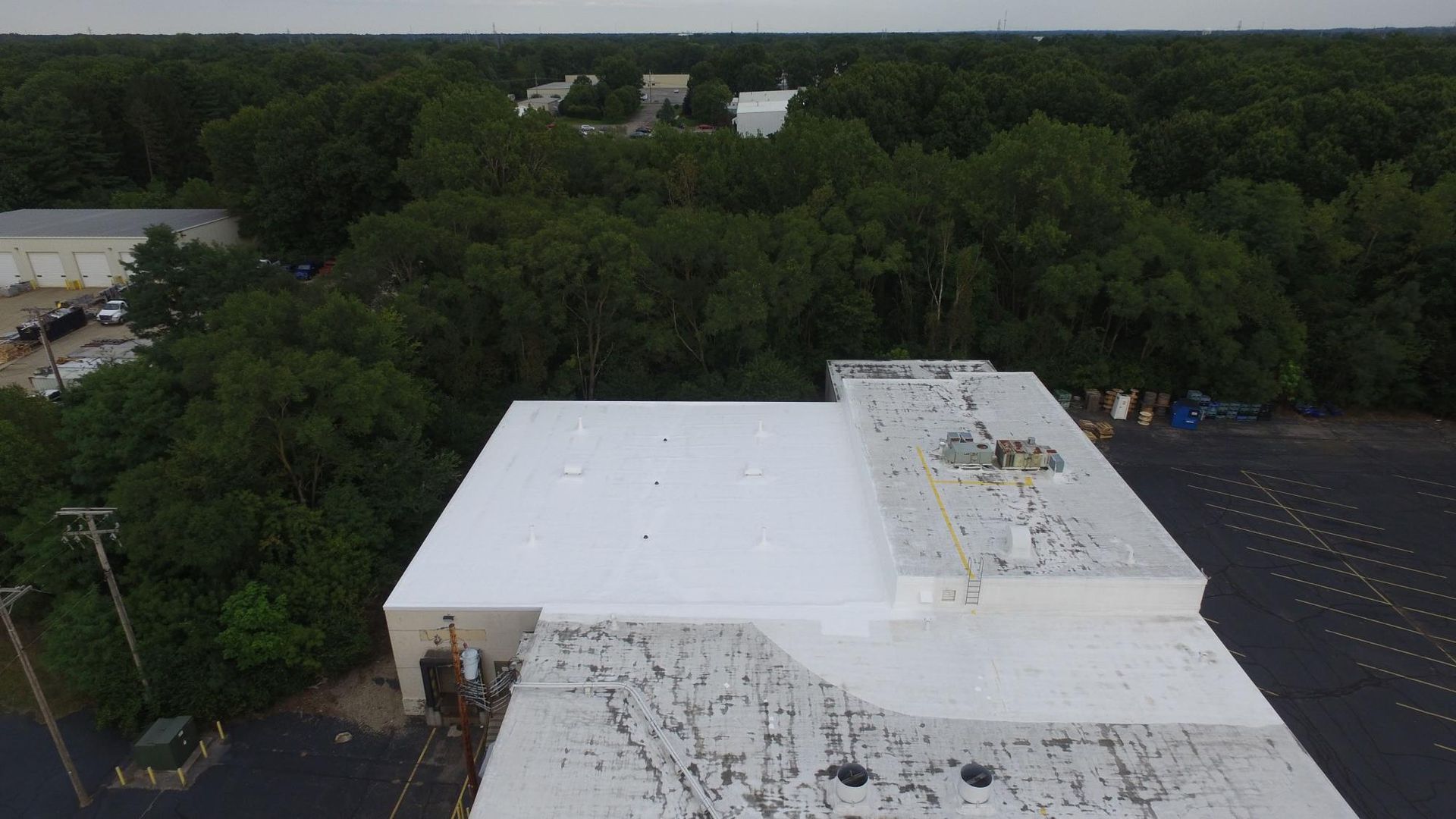 An aerial view of a white roof with trees in the background.