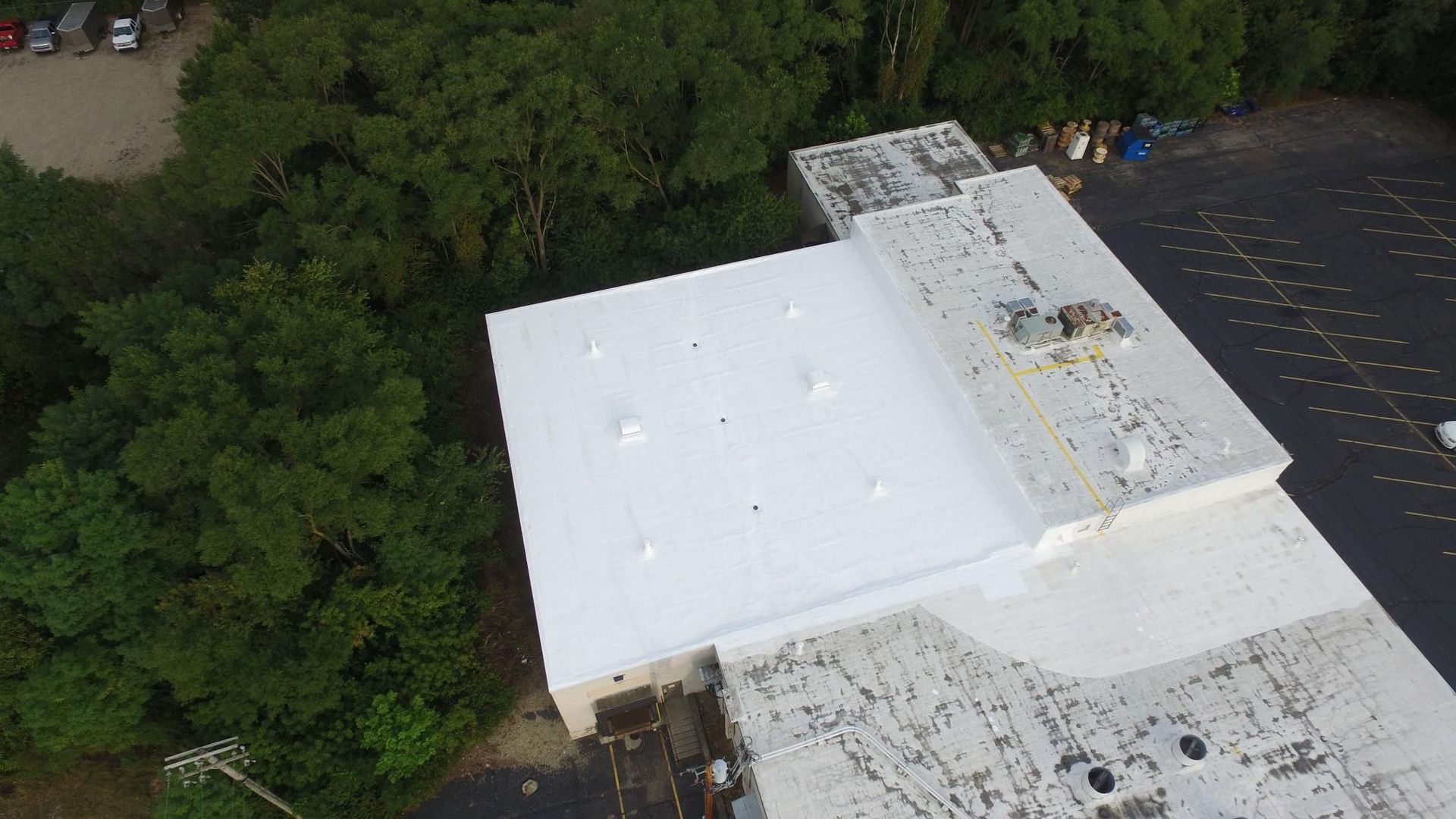 An aerial view of a white roof with trees in the background.