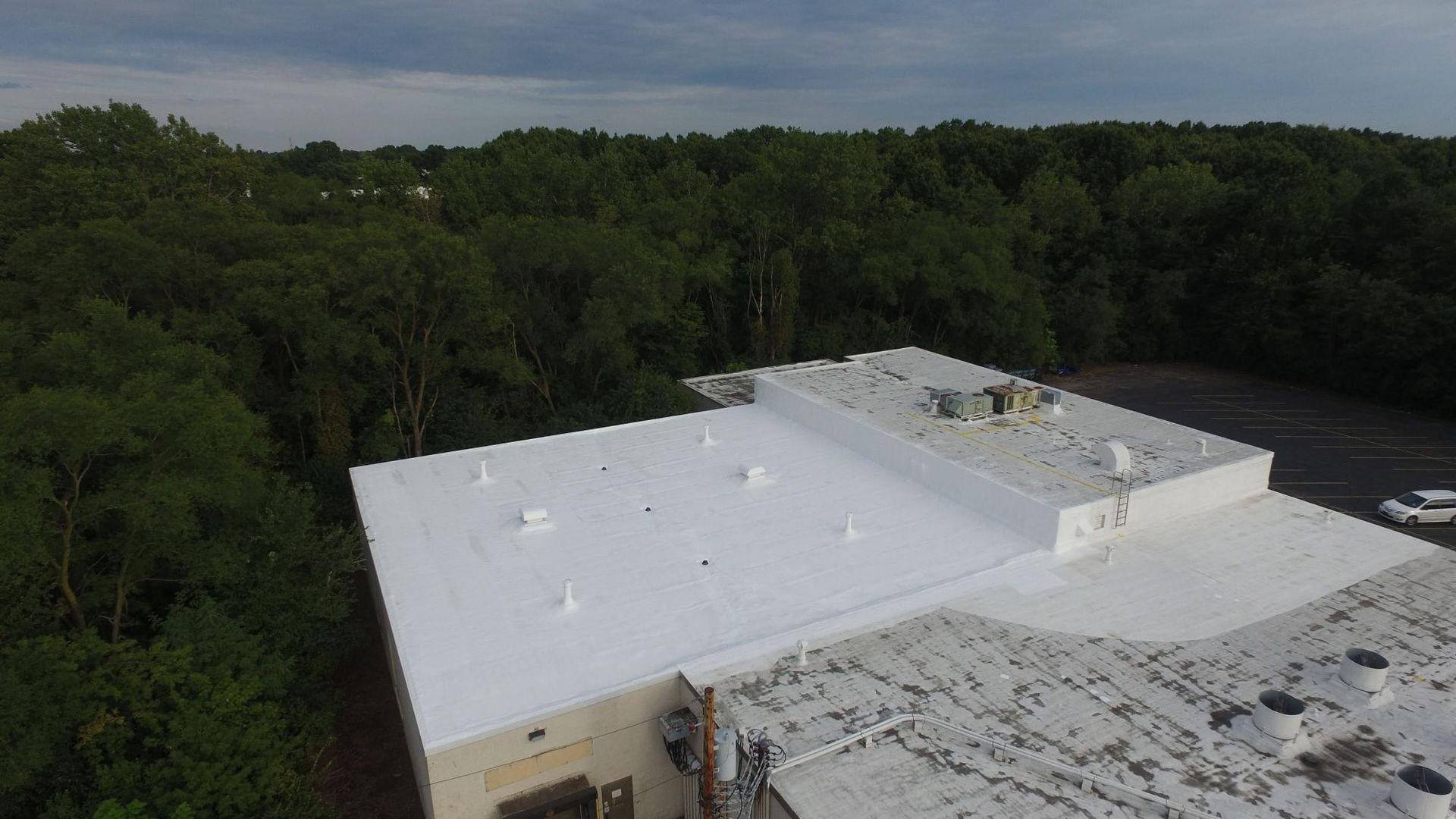 An aerial view of a white roof with trees in the background.