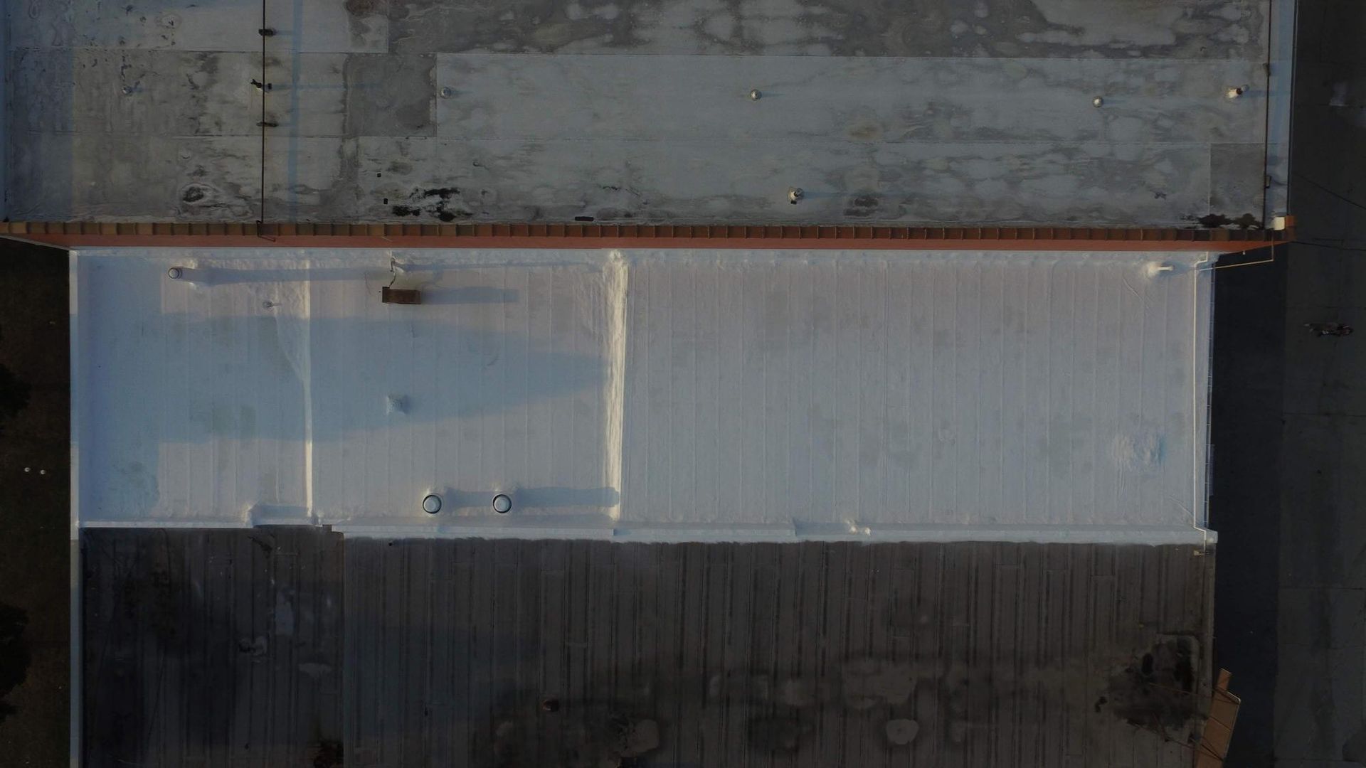 An aerial view of a large building with a white roof.