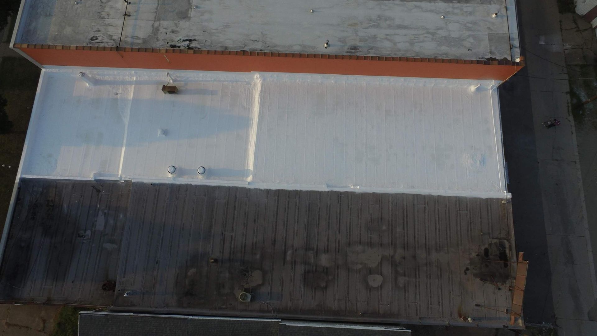 An aerial view of a building with a white roof and a black roof.