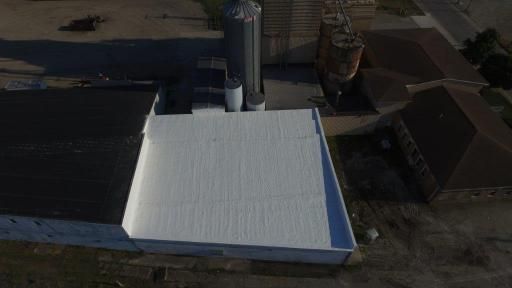 An aerial view of a building with a white roof and silos.