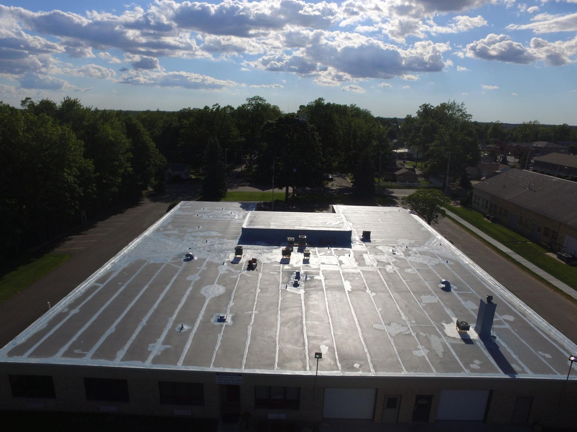 An aerial view of the roof of a building with trees in the background