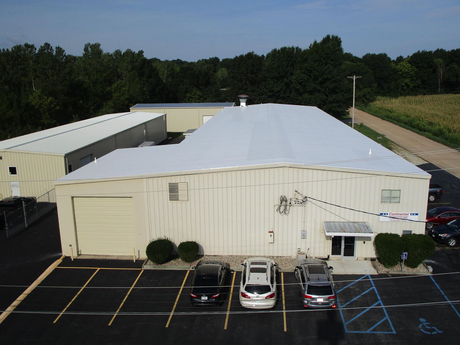 An aerial view of a large white building with cars parked in front of it.