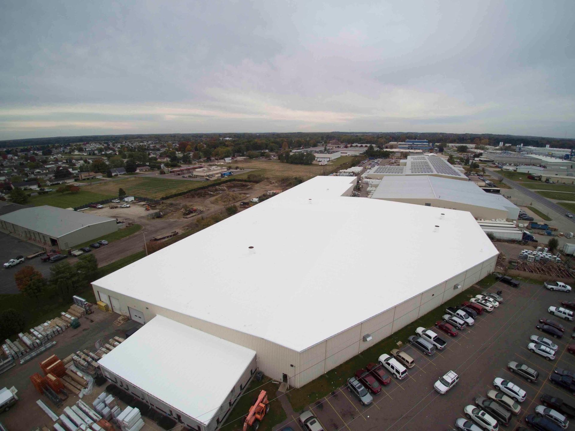 An aerial view of a large white building with a parking lot in front of it.