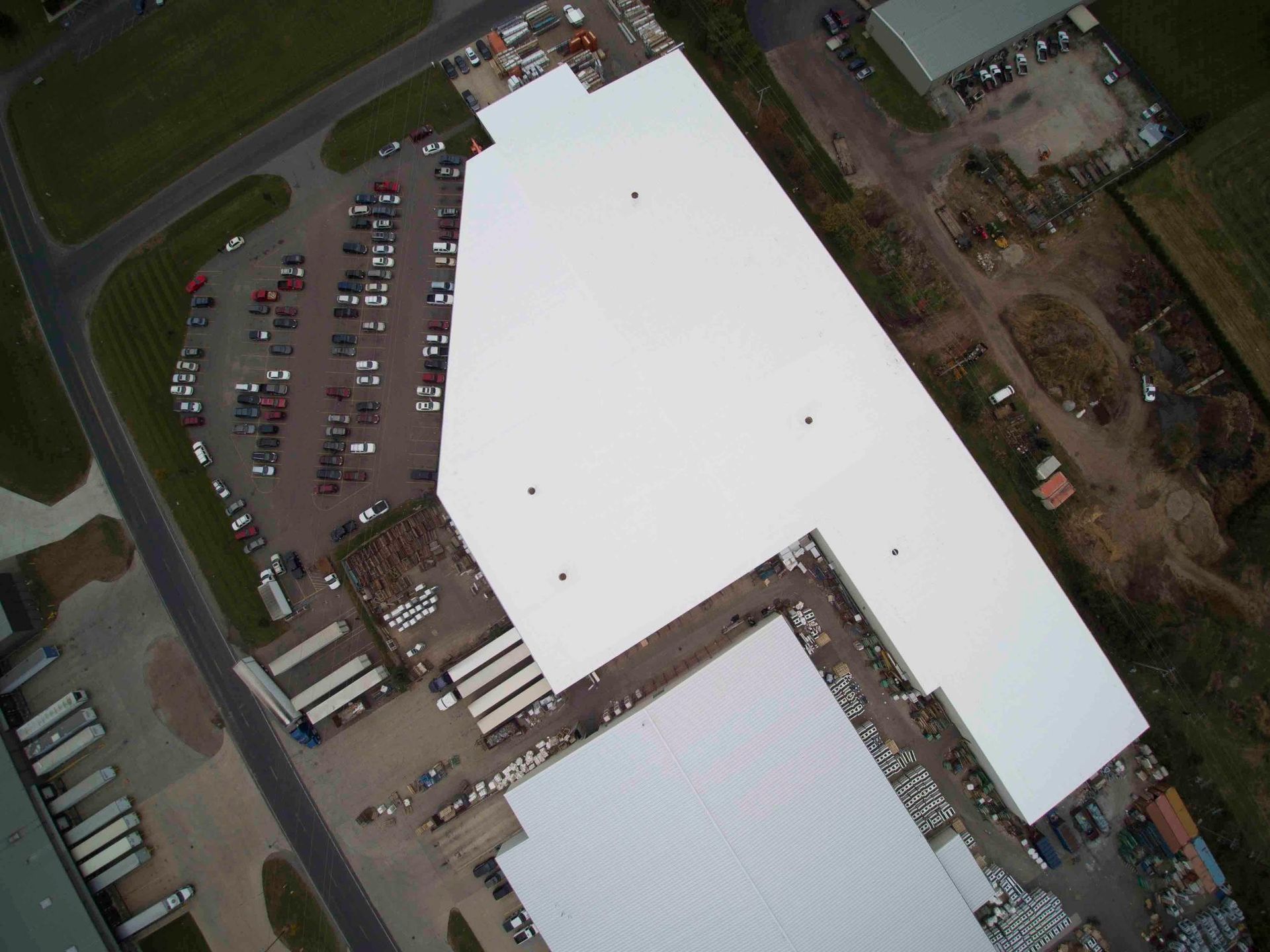 An aerial view of a large white building with a parking lot in front of it.