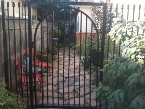 A black wrought iron gate leading to a stone walkway
