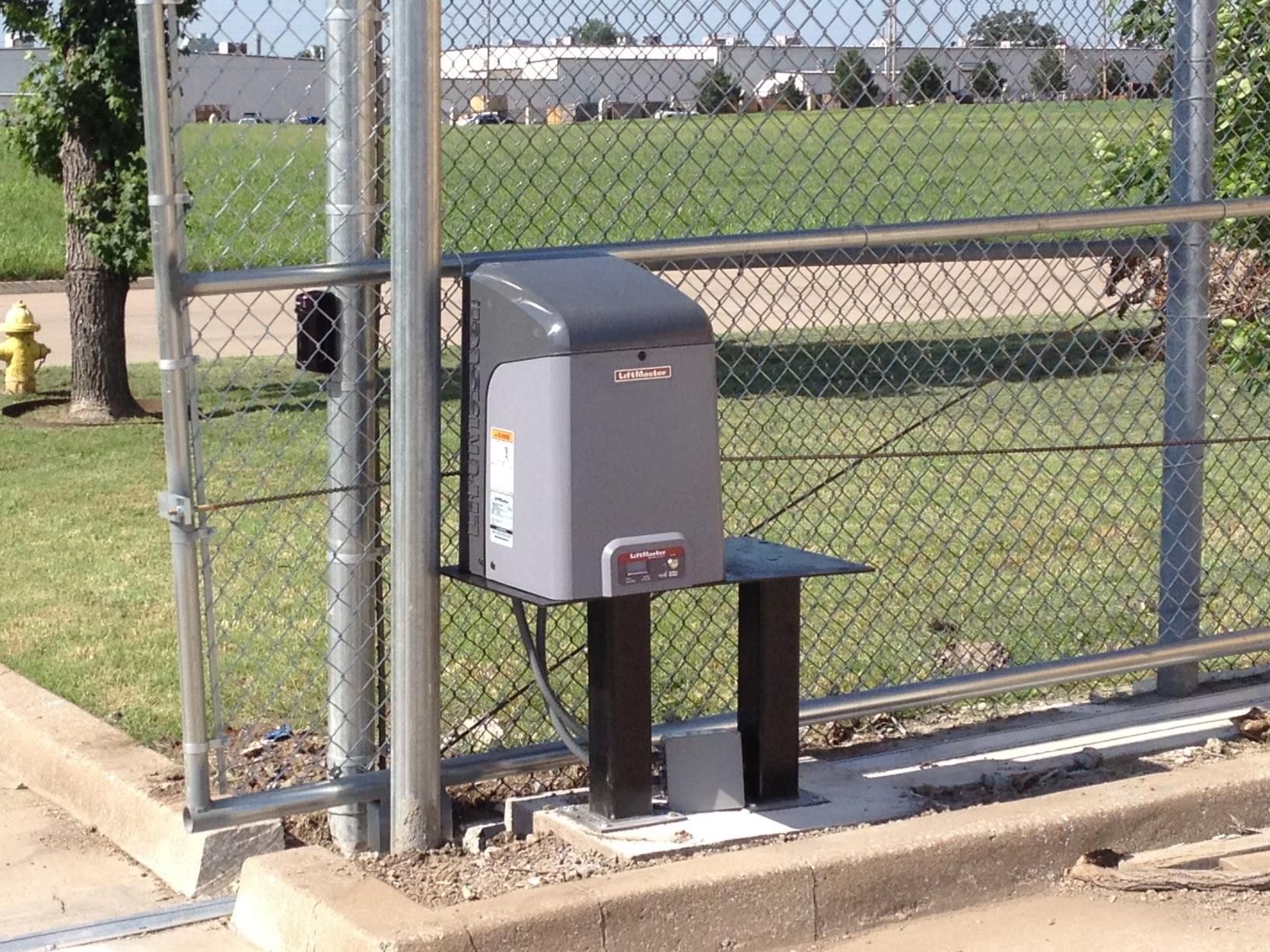 A fence with a sliding gate and a fire hydrant in the background