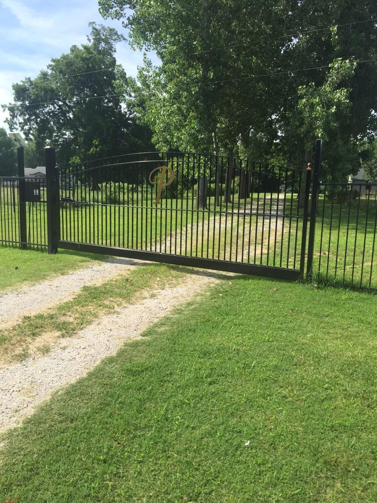 A fence surrounds a grassy field with trees in the background.