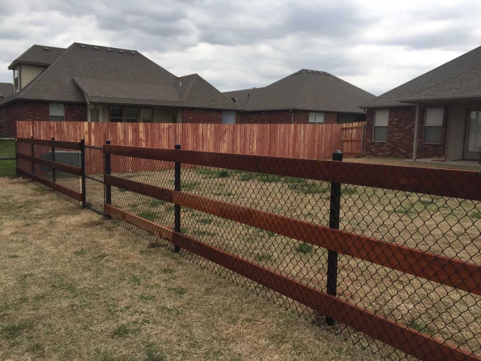 A chain link fence with a wooden fence in front of a house