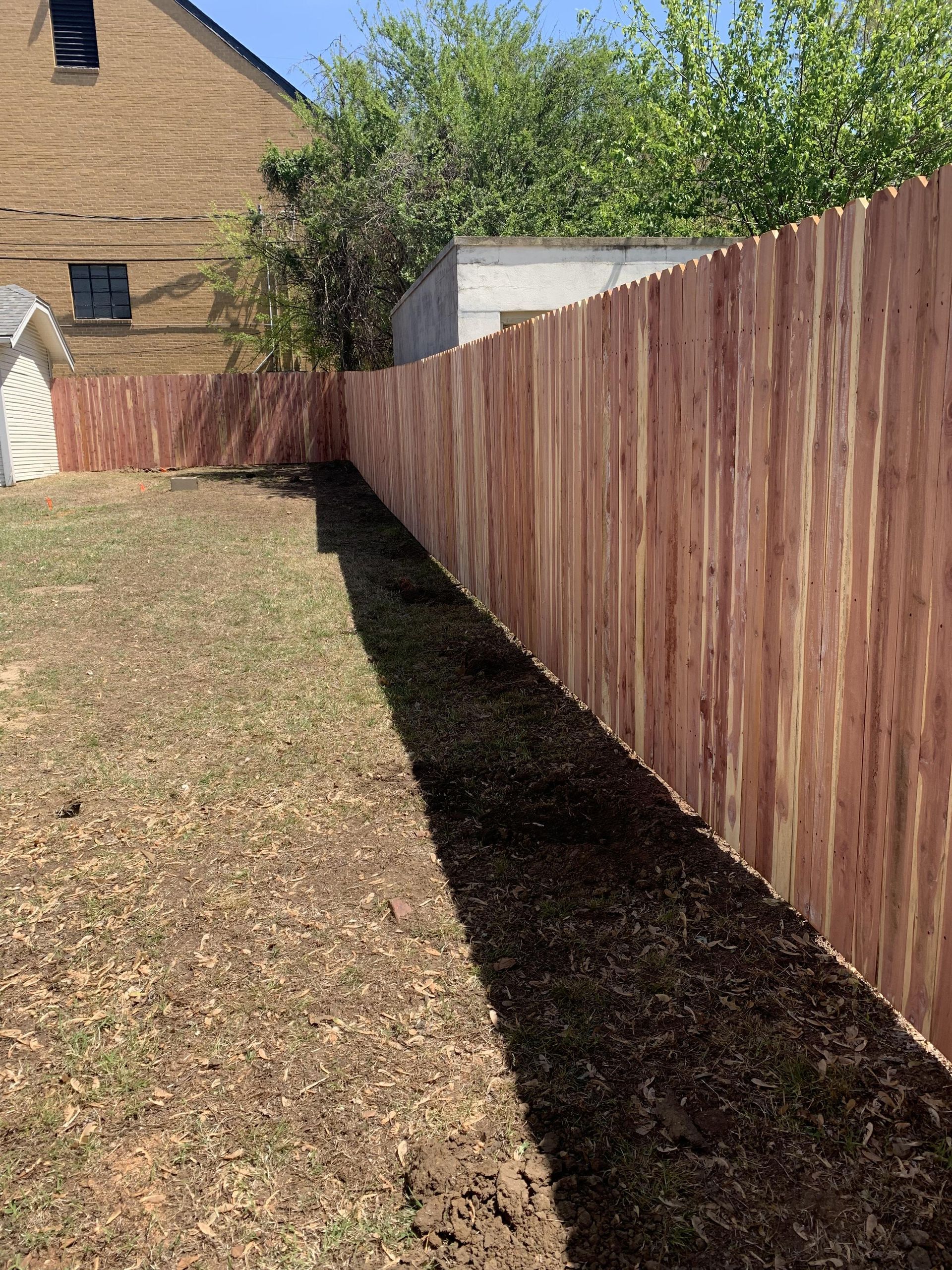 A wooden fence is in the backyard of a house.