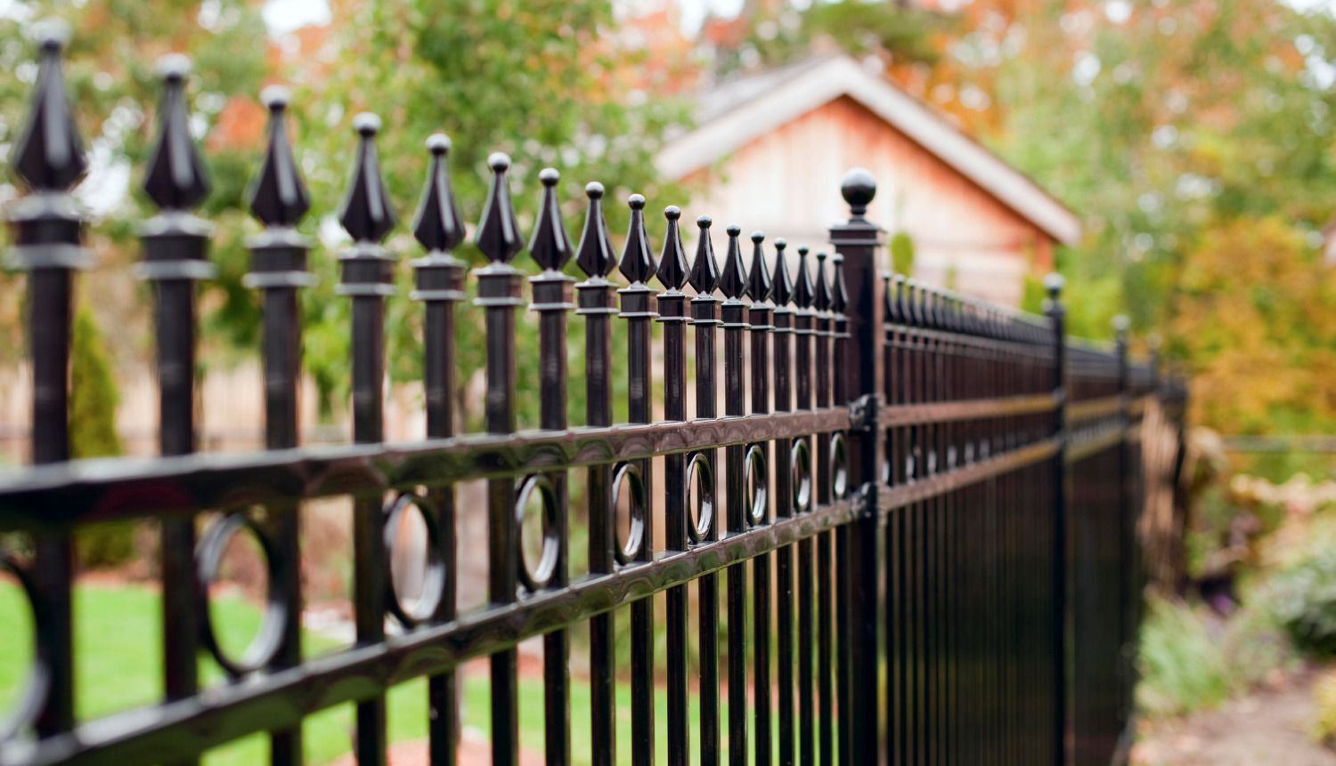 A close up of a black wrought iron fence in front of a house.