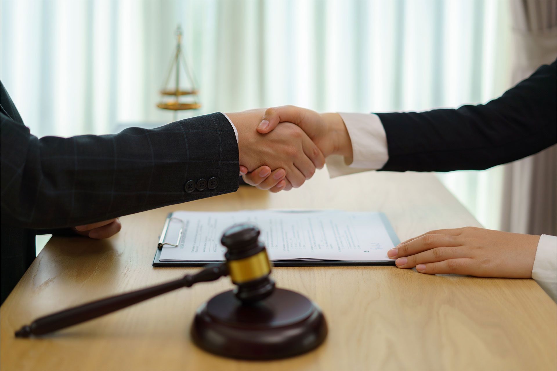 A man and a woman are shaking hands in front of a judge 's gavel.