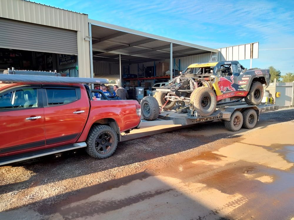 A Red Truck Is Towing A Buggy On A Trailer — AHT Towing in Ciccone, NT