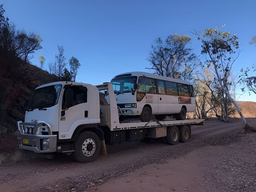 A Tow Truck With A Bus On The Back Of It — AHT Towing in Ciccone, NT
