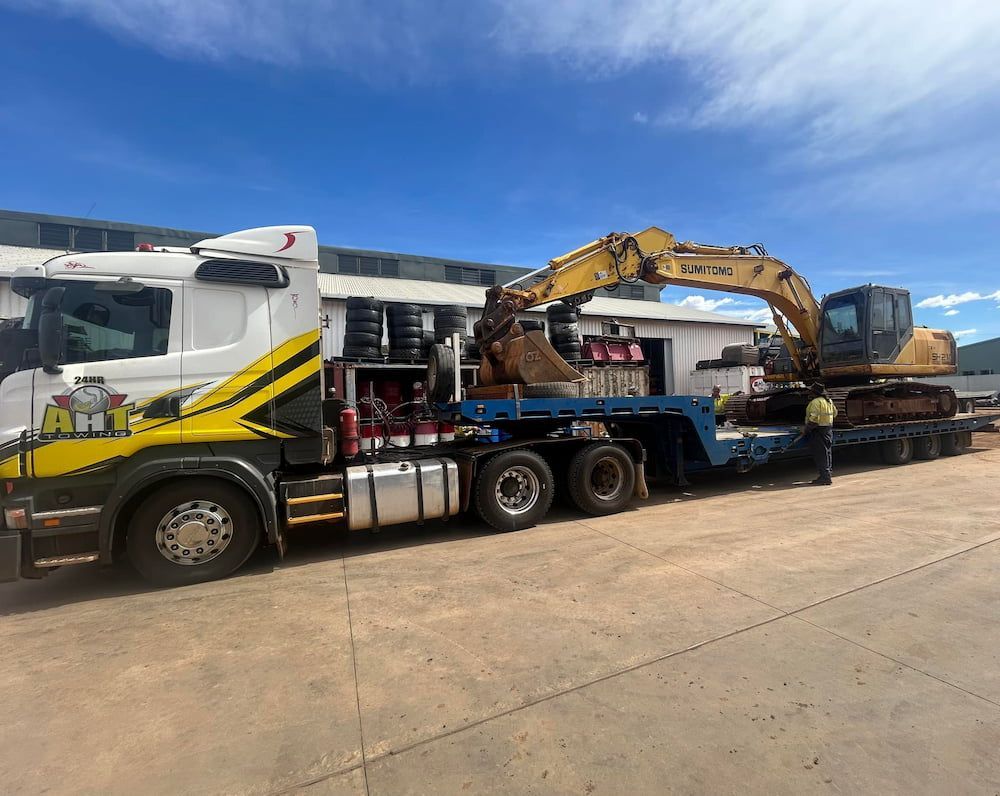 A Truck Is Carrying A Large Excavator On A Trailer — AHT Towing in Ciccone, NT