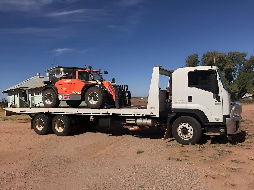 A Tow Truck Is Carrying A Forklift On The Back Of It — AHT Towing in Ciccone, NT