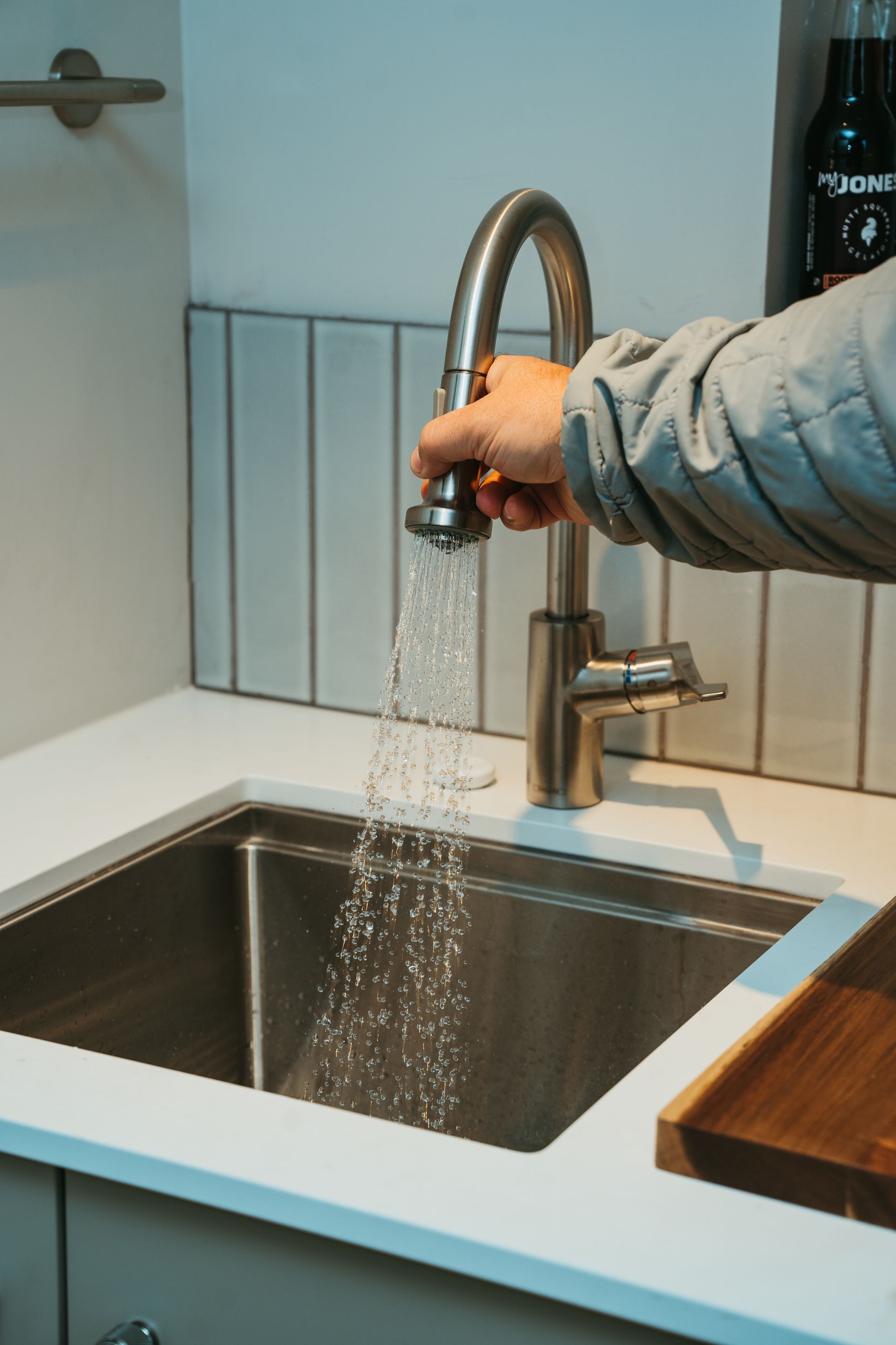 A person is pouring water from a faucet into a sink.