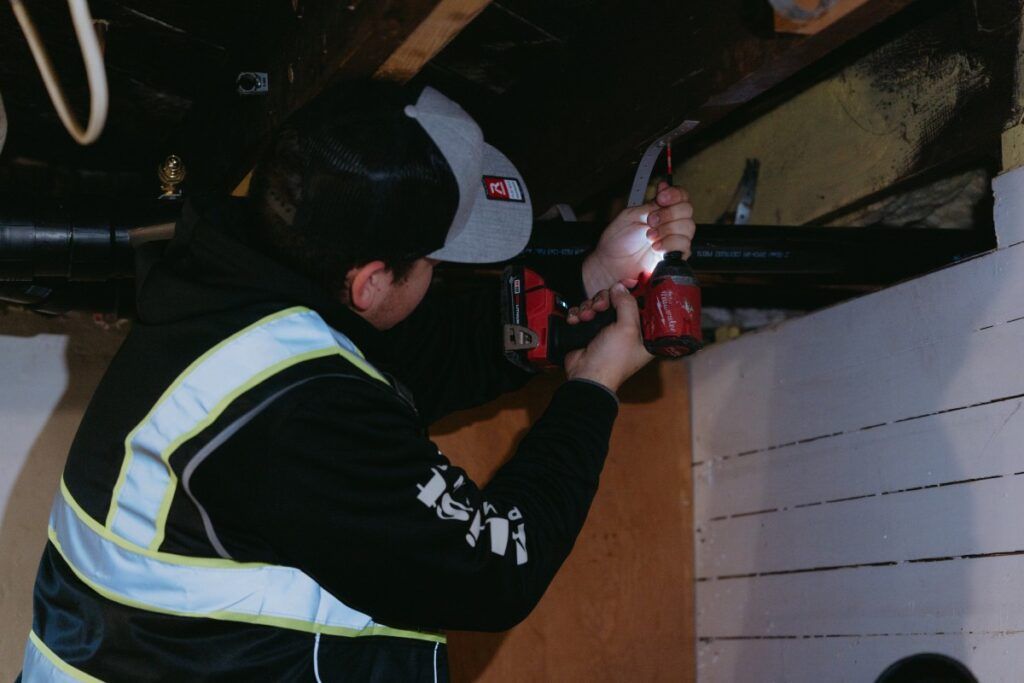 A man in a safety vest is working on a pipe