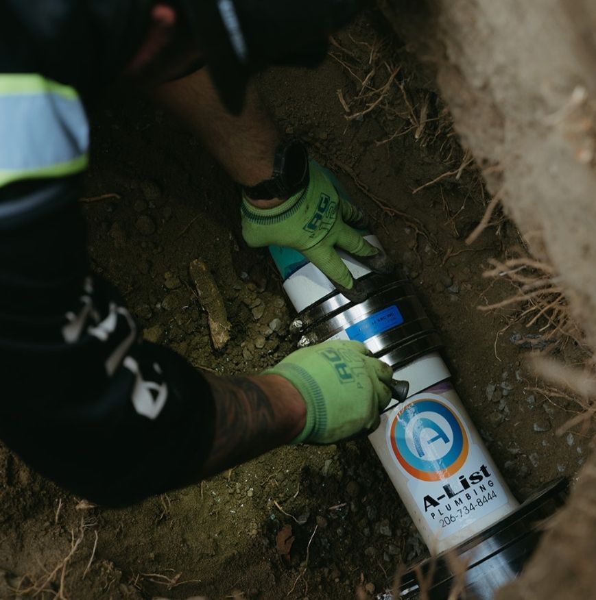 A man wearing green gloves is working on an a-list pipe