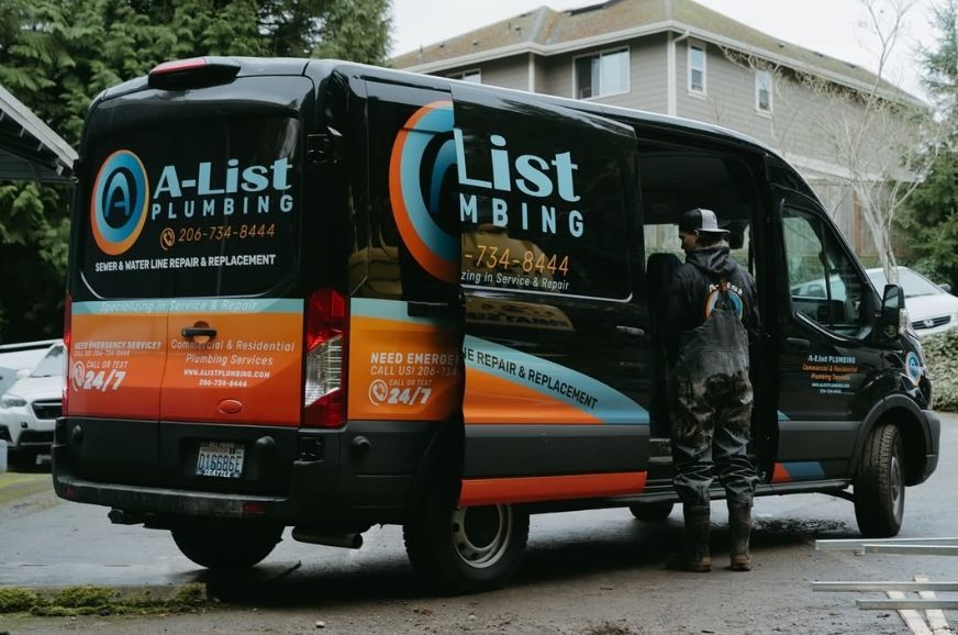 A man is getting out of a a-list plumbing van.