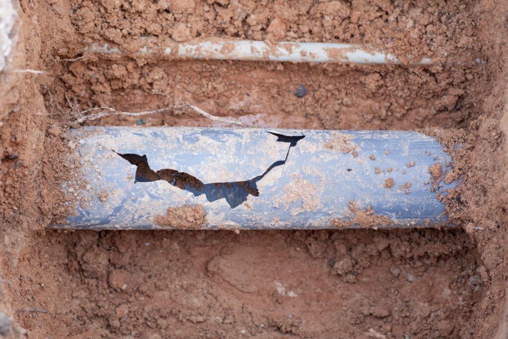A close up of a broken pipe in the dirt.