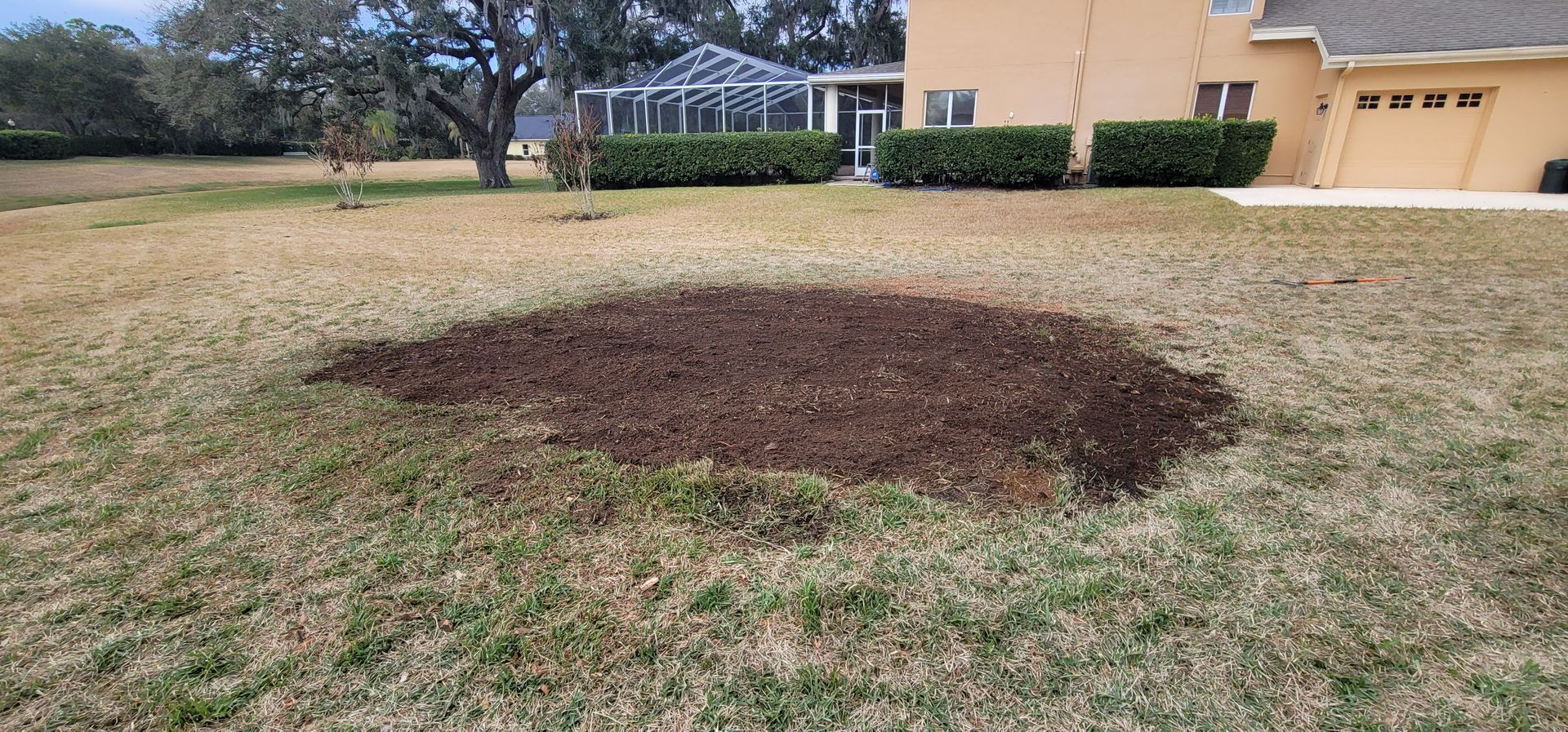 A large hole in the grass in front of a house.