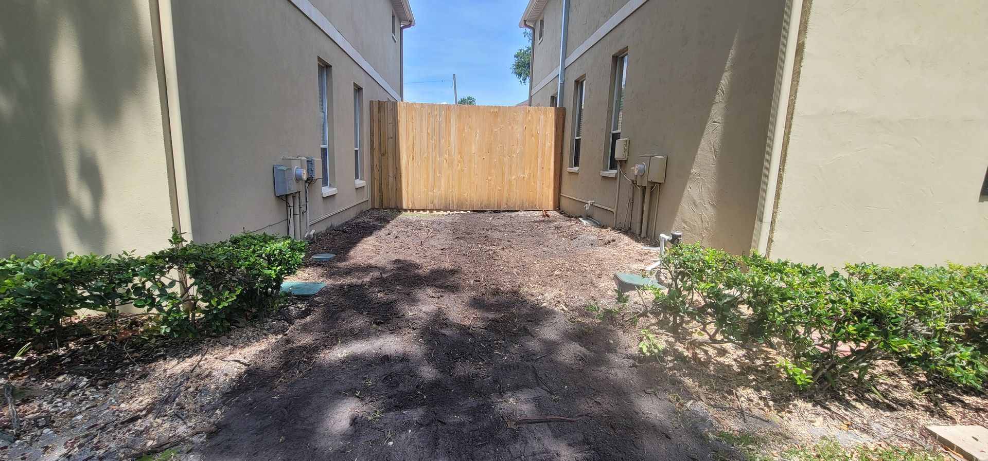 There is a wooden fence between two buildings.