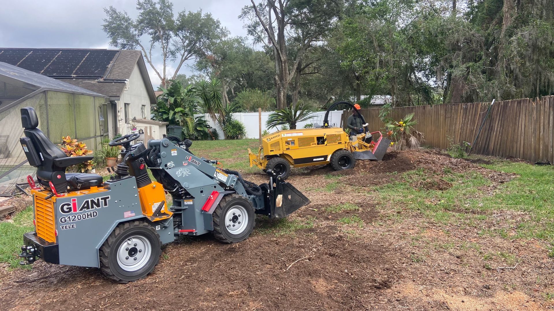 A couple of tractors are parked in a yard.