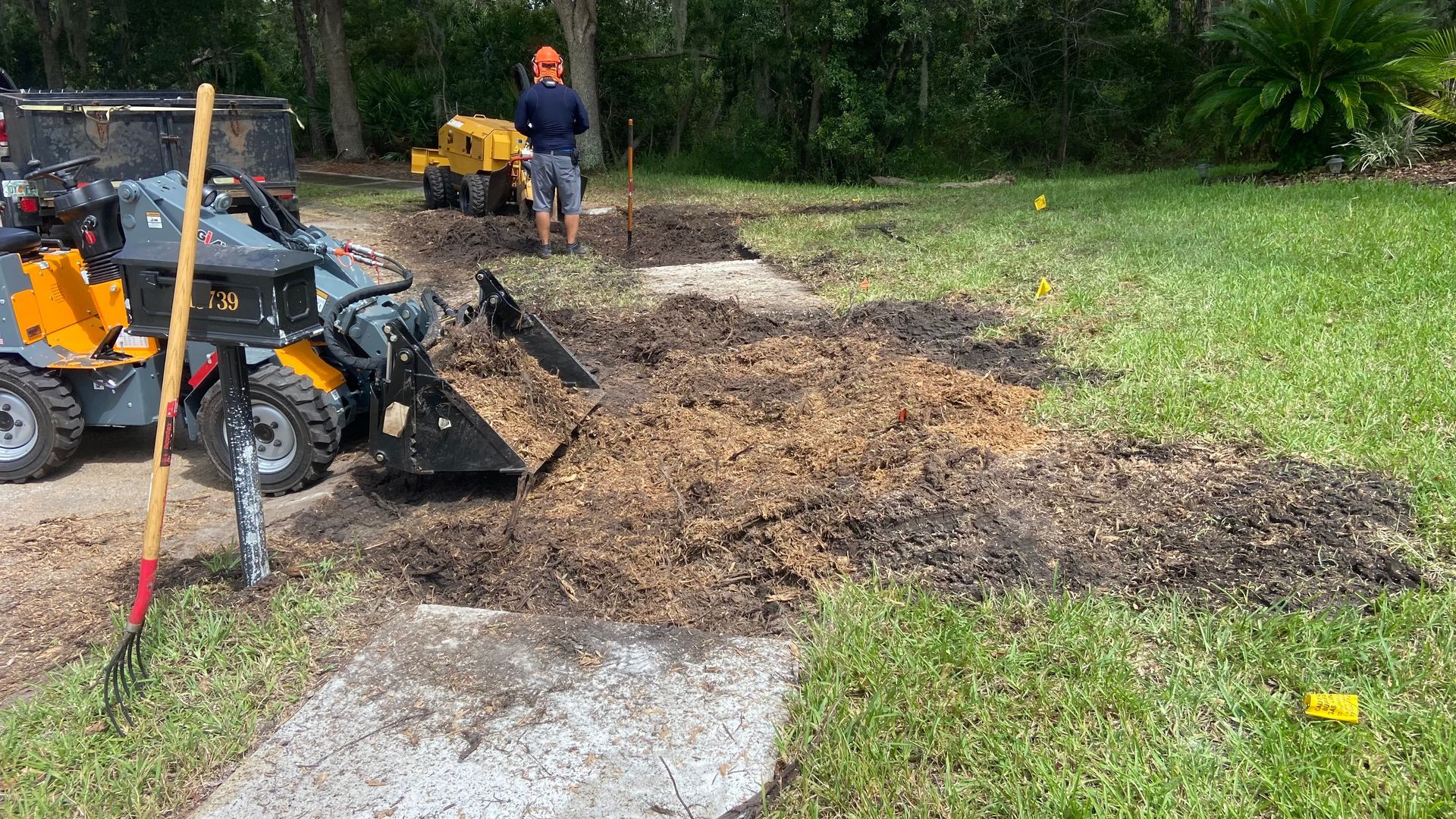 A man is working on a stump grinder in a yard.