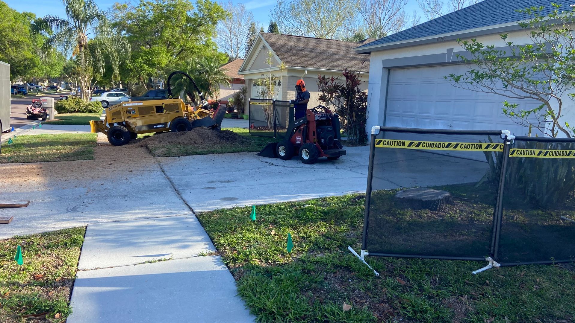 A tree stump grinder is being used to remove a tree stump from a driveway.