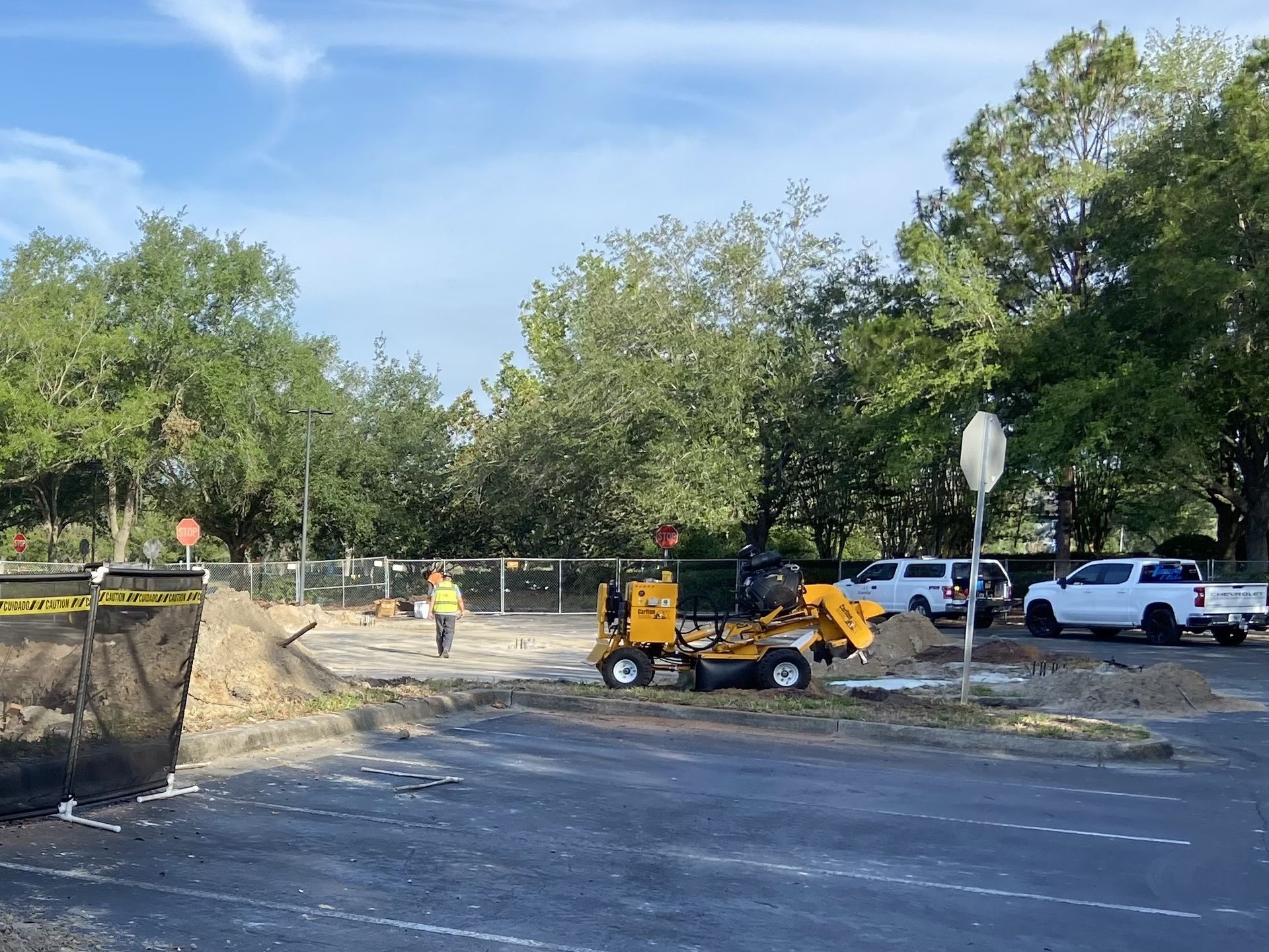 A construction site with a lot of stump grinding trucks parked on the side of the road.