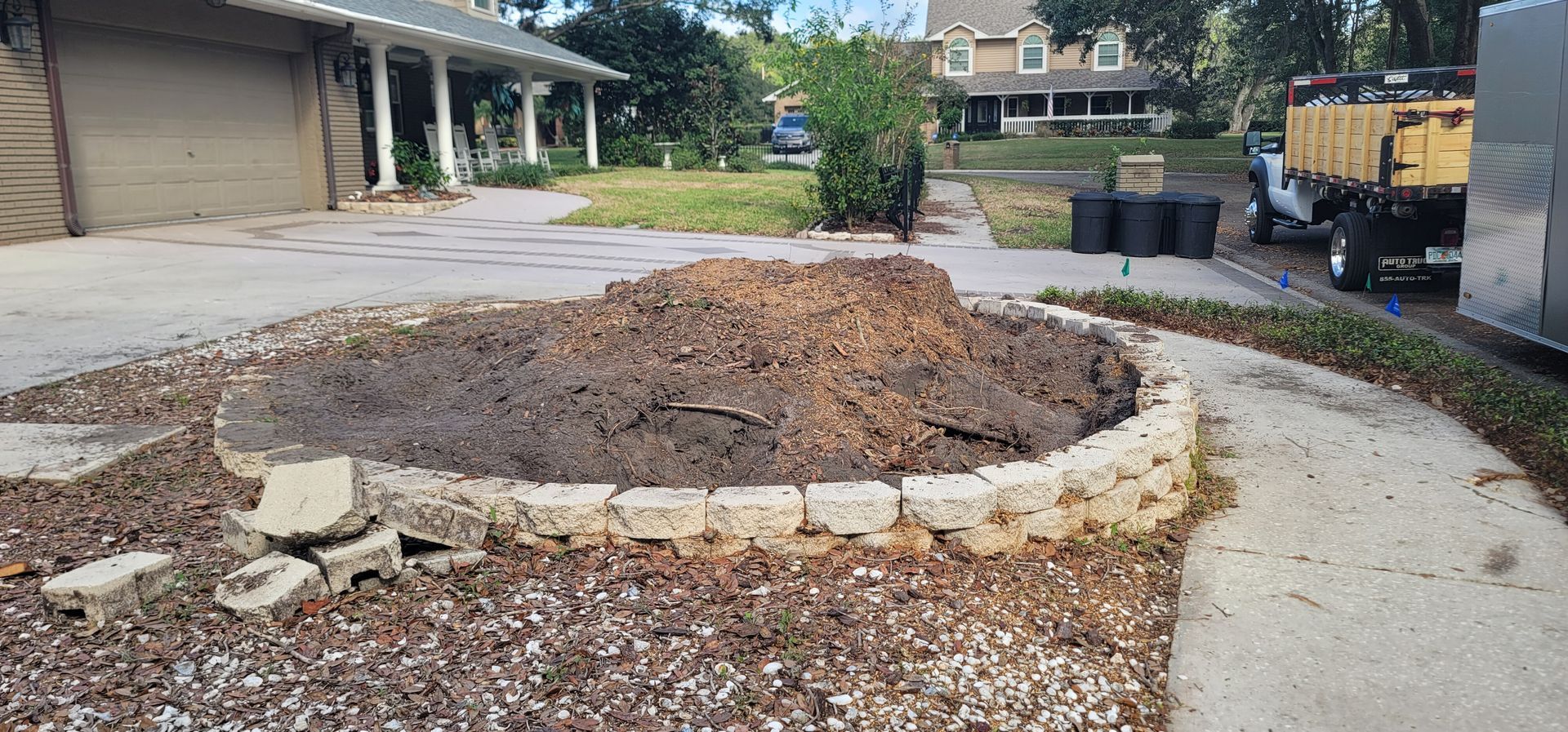 A pile of dirt is sitting in the middle of a driveway next to a house.