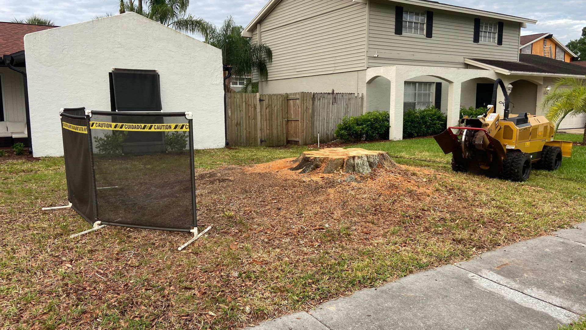 A stump grinder is sitting in front of a house.