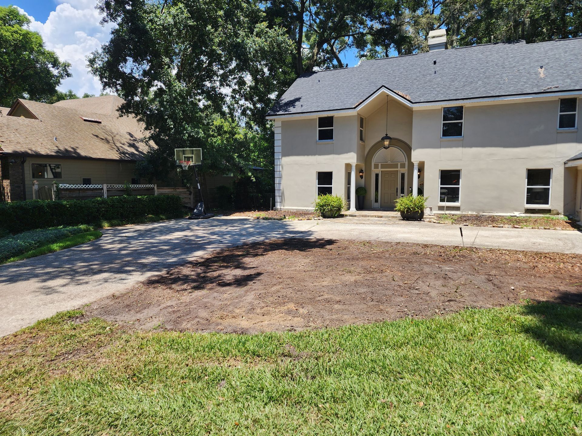 A large white house with a basketball hoop in the backyard.