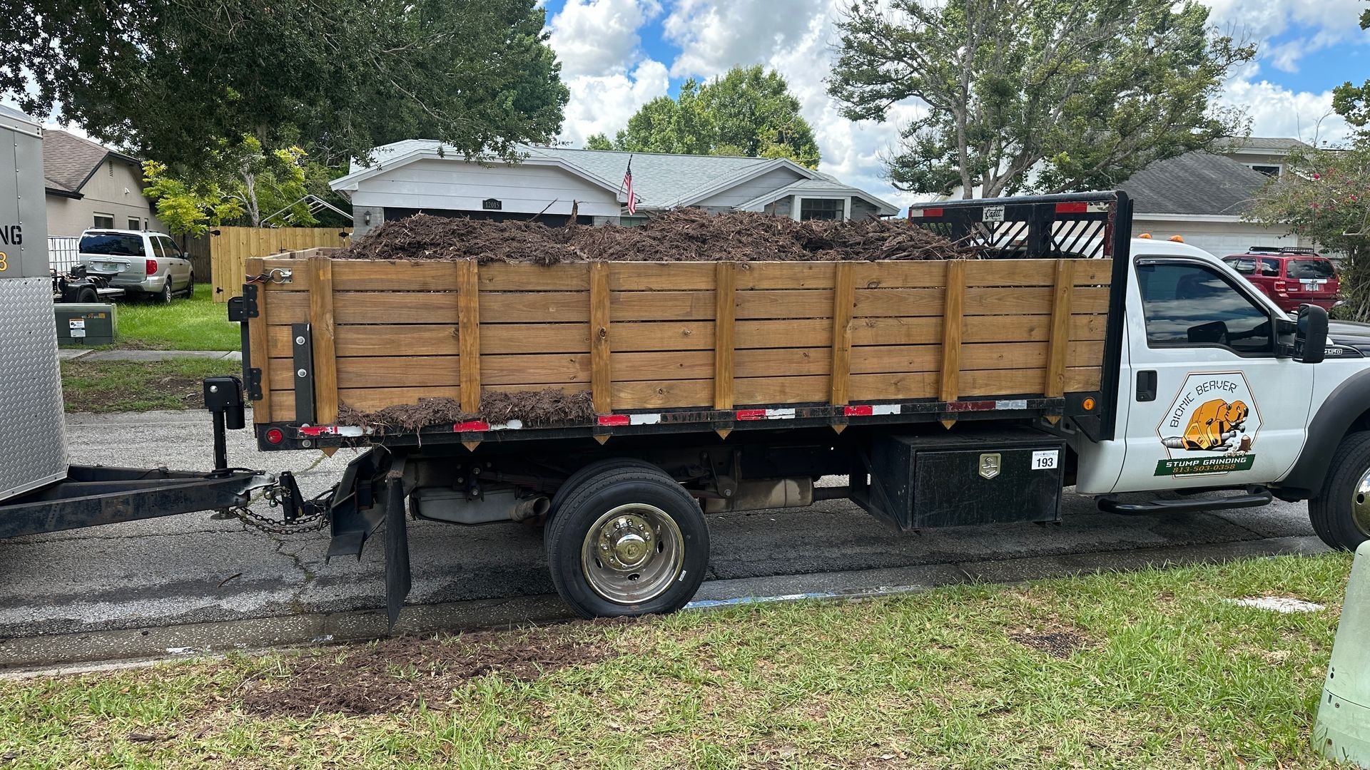 A white truck with a wooden bed is parked in a yard.