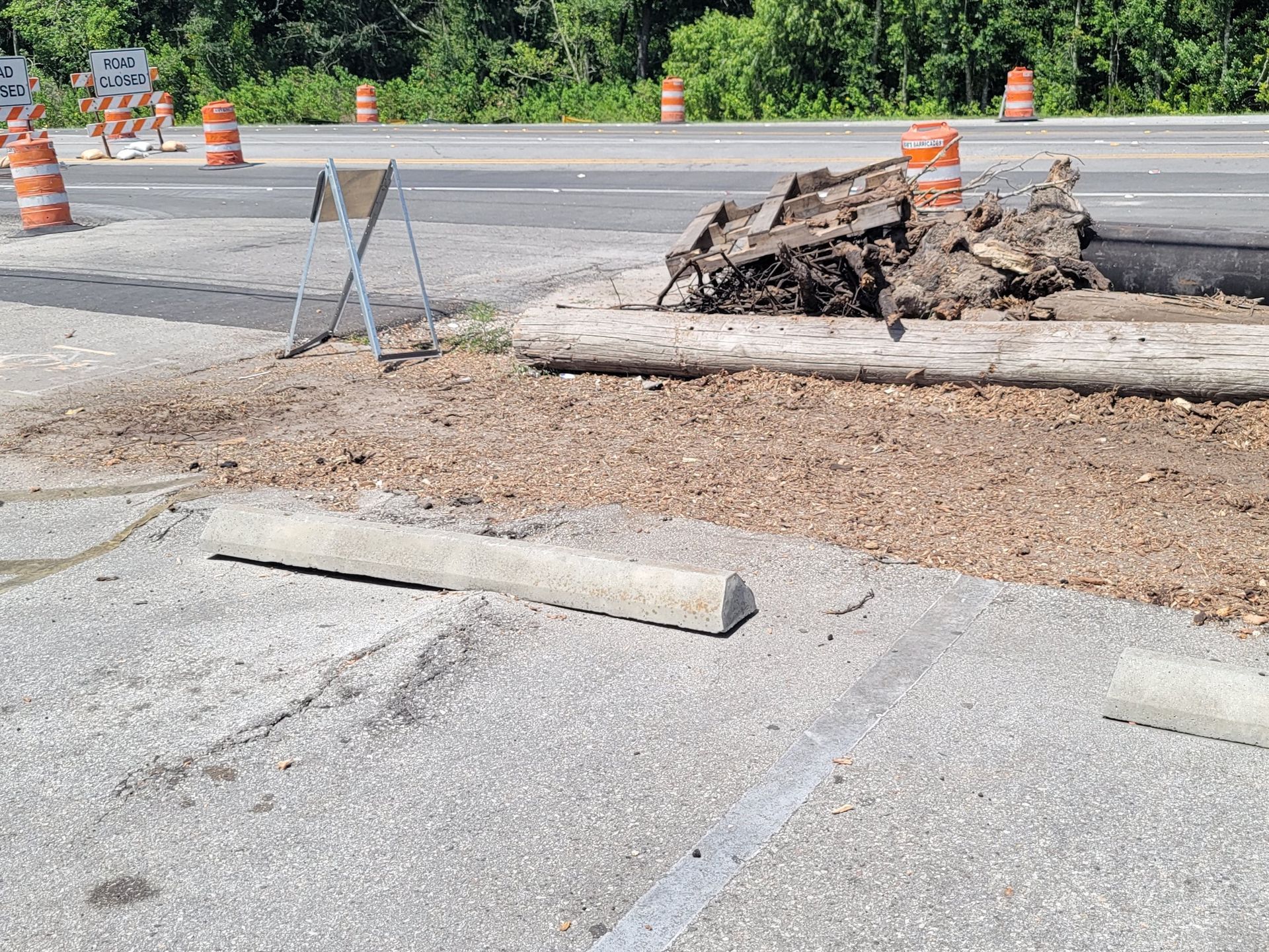 A concrete curb is sitting on the side of the road next to a pile of wood.