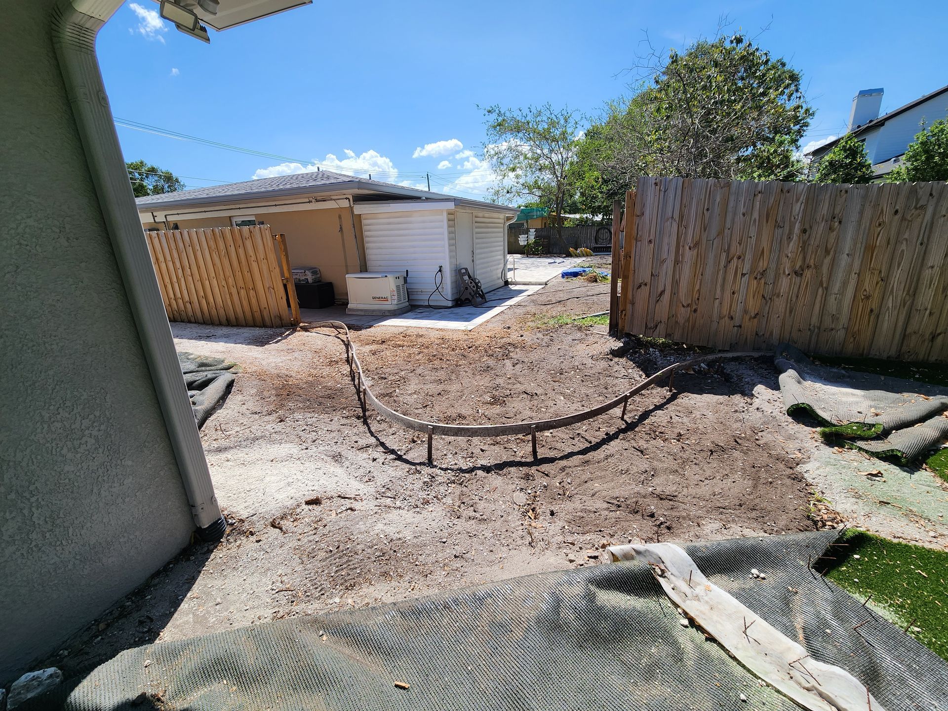 A backyard with a fence and a house in the background.