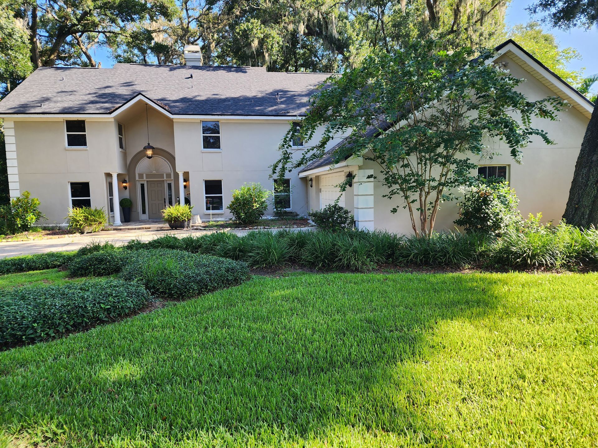 A large white house with a lush green lawn in front of it.