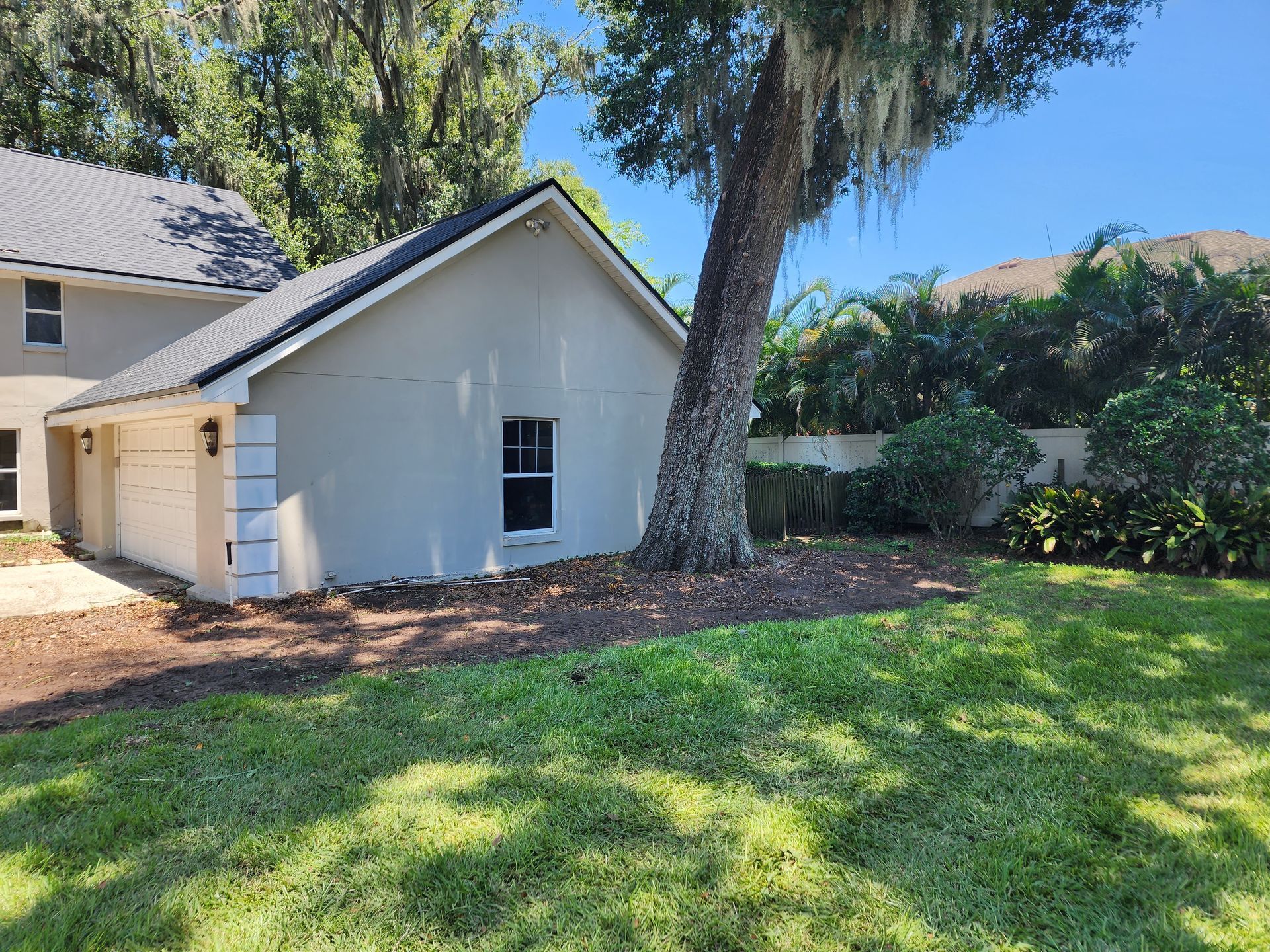 A house with a garage and a tree in front of it.