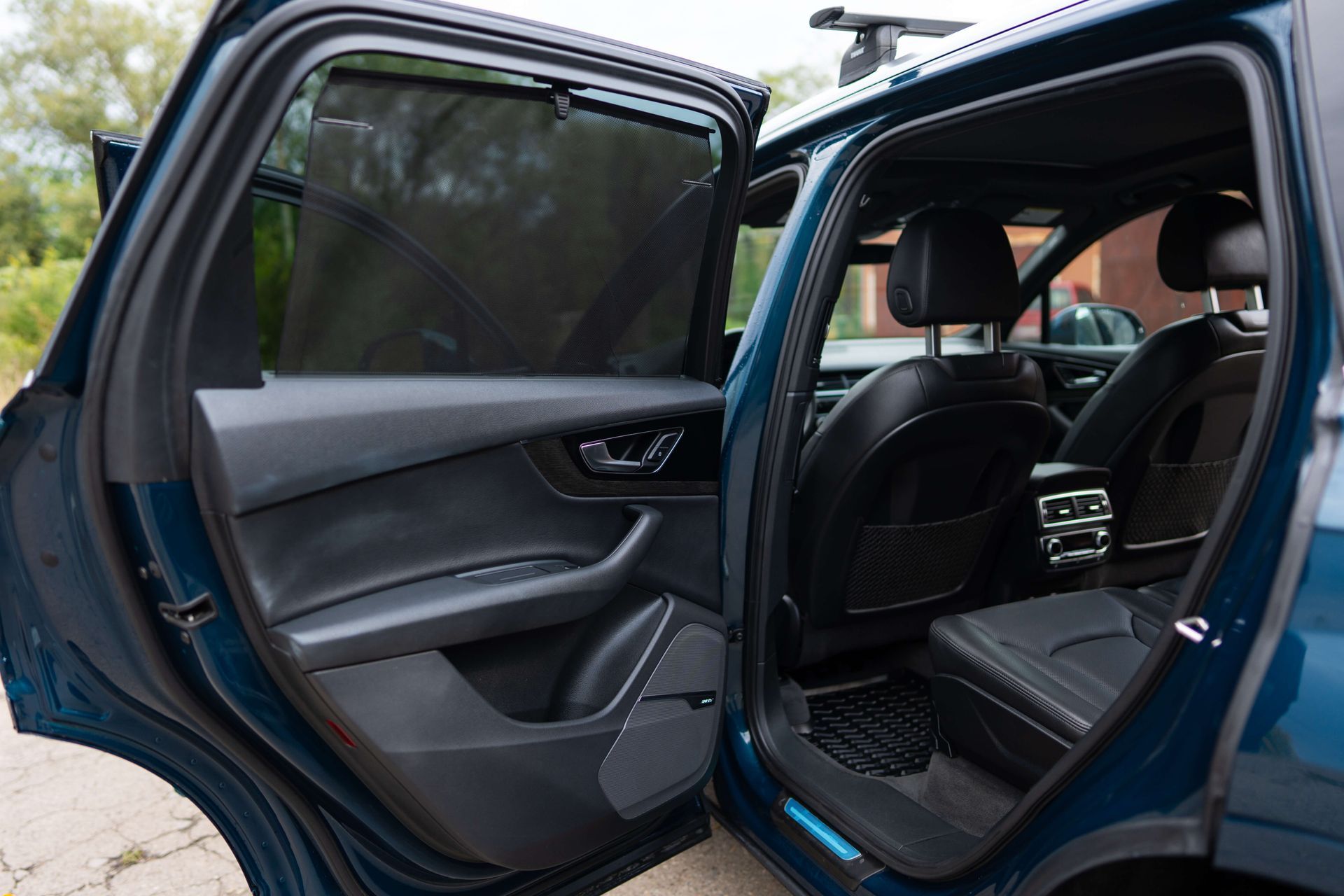 The back seat of a blue car with the door open.